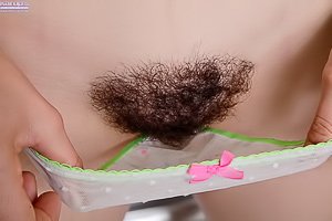 Dark-haired hottie with a bushy pussy masturbating in the kitchen